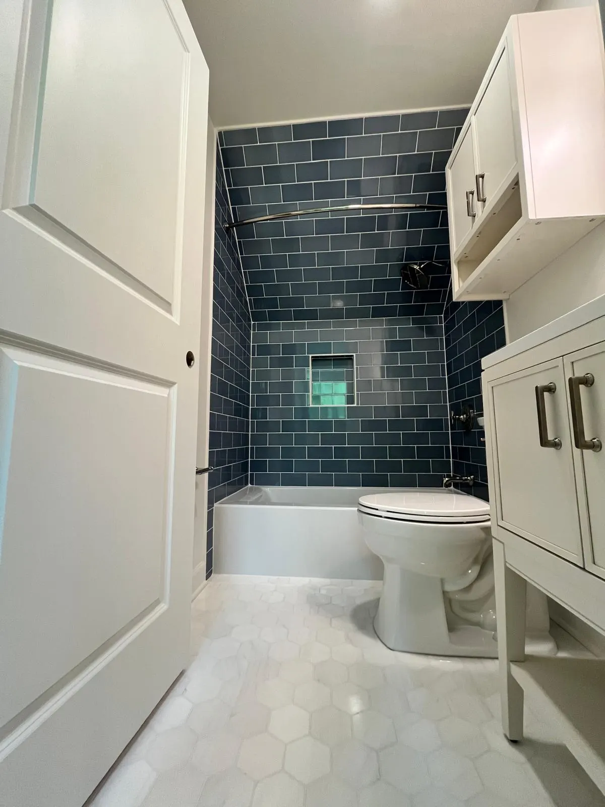 Baño terminado con ducha revestida en cerámica oscura y tocador blanco